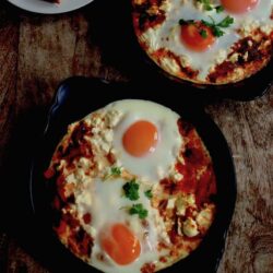 2 Shakshuka dishes with toast on a table