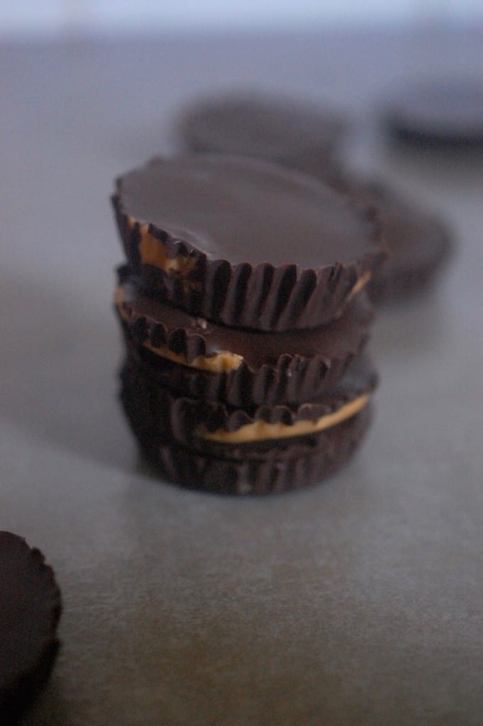 3 Chocolate Peanut butter cups piled on top of each other on grey background