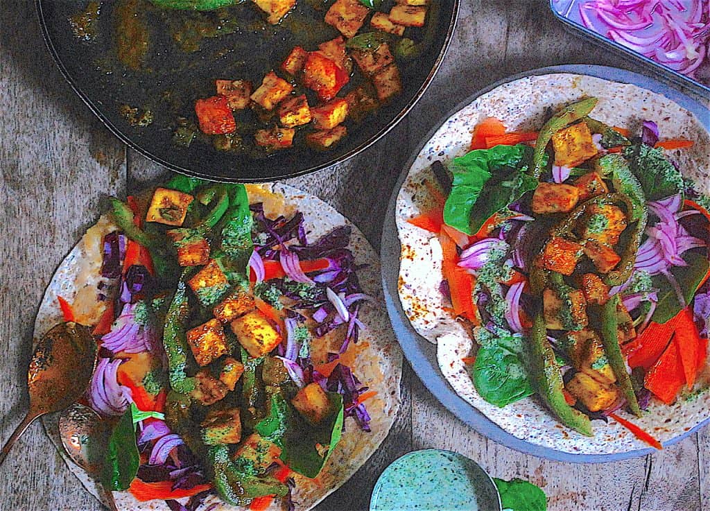 Paneer wraps on a table with mint sauce and red onions