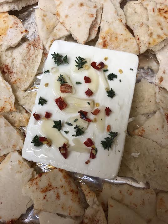 Feta with oil, thyme, red chilli and thyme on bed of feta in tray