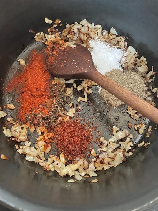 Spices and tomato puree added to pot