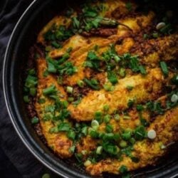 Masala Fish in a pan topped with spring onions and coriander