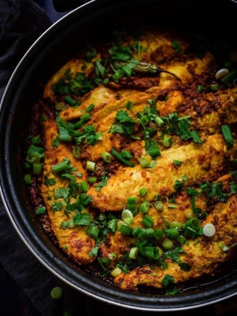 Fish in a Masala Sauce with Spring Onions and Coriander on top in a large pan