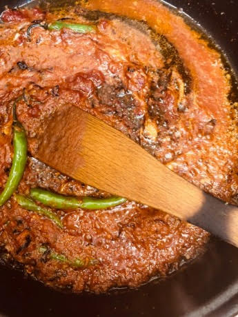 Tomato curry in pan with wooden spatula