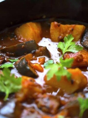 Aubergine and Potato curry in black pot with coriander
