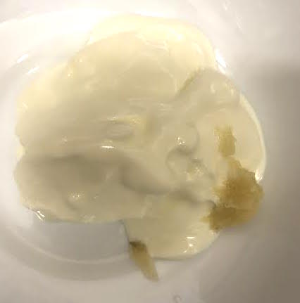 Yoghurt and garlic in bowl over pot of water