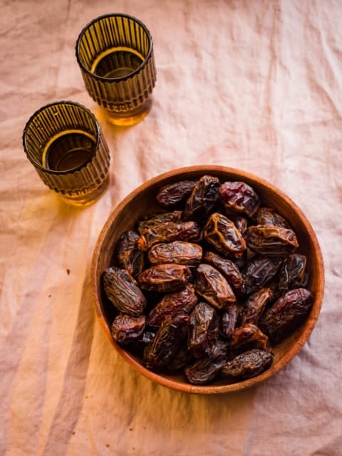 Dates in a bowl with 2 cups of water to side