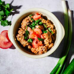 Ful Medames in a bowl with vegetables around the bowl