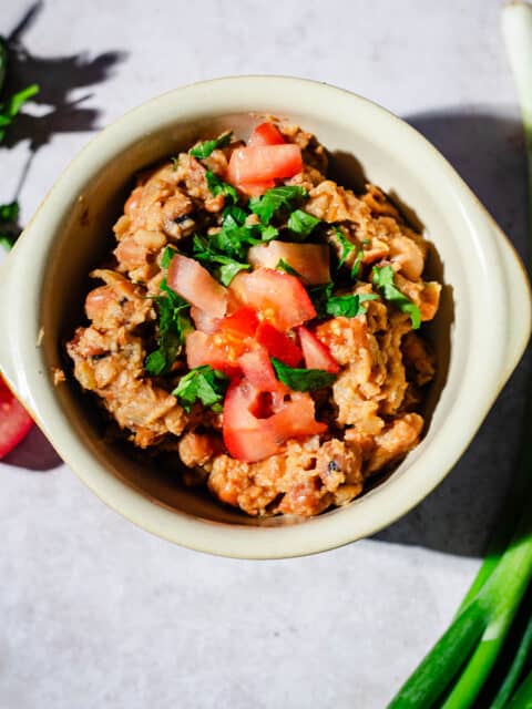 Ful Medames in a bowl with vegetables around the bowl