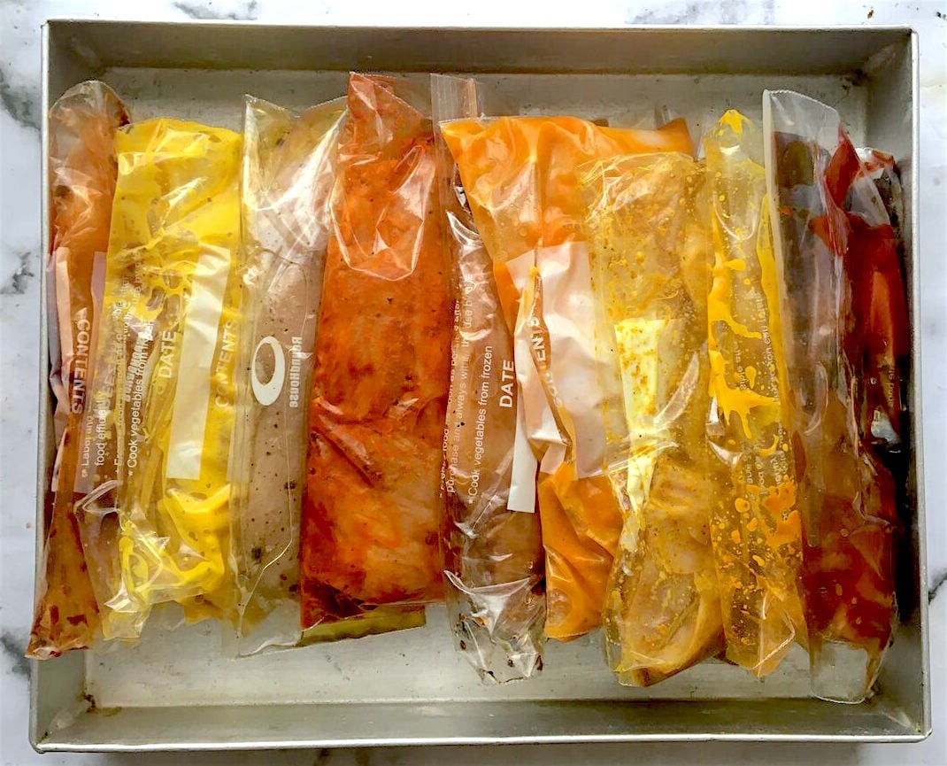 Different marinated chicken in freezer bags on a silver tray