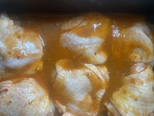 Chicken thighs with peri peri sauce on top in oven tray 
