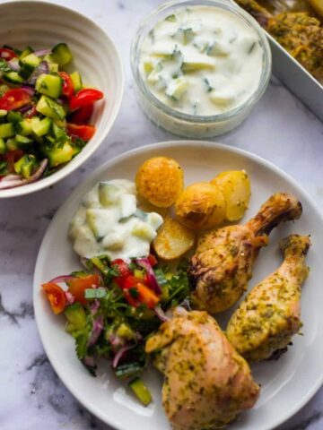 Greek chicken in a plate with potatoes and salad