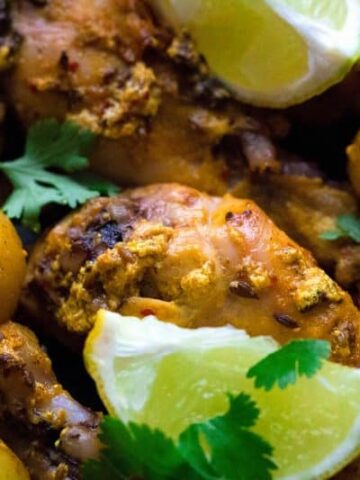 Roasted Chicken Legs with Baby Potatoes in indian spices with lemon slices. close up shot