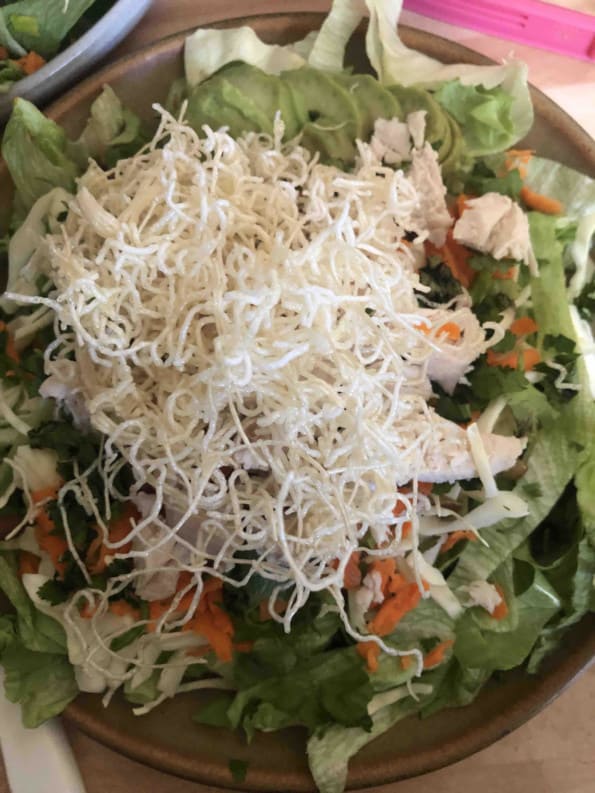 Noodles added to salad in plate