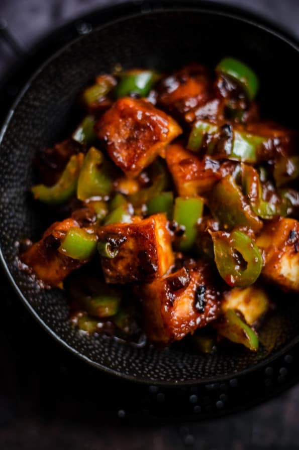 Chilli Paneer with peppers in a black bowl