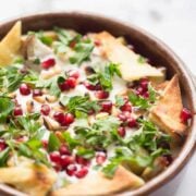 Aubergine Fetteh in bowl topped with pomegranate and toasted pitta
