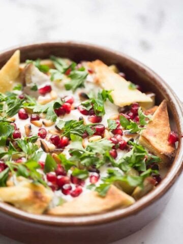 Aubergine Fetteh in bowl topped with pomegranate and toasted pitta