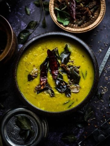 Masoor Dal Tadka in bowl with red chilli, curry leaves, garlic and cumin seeds on top