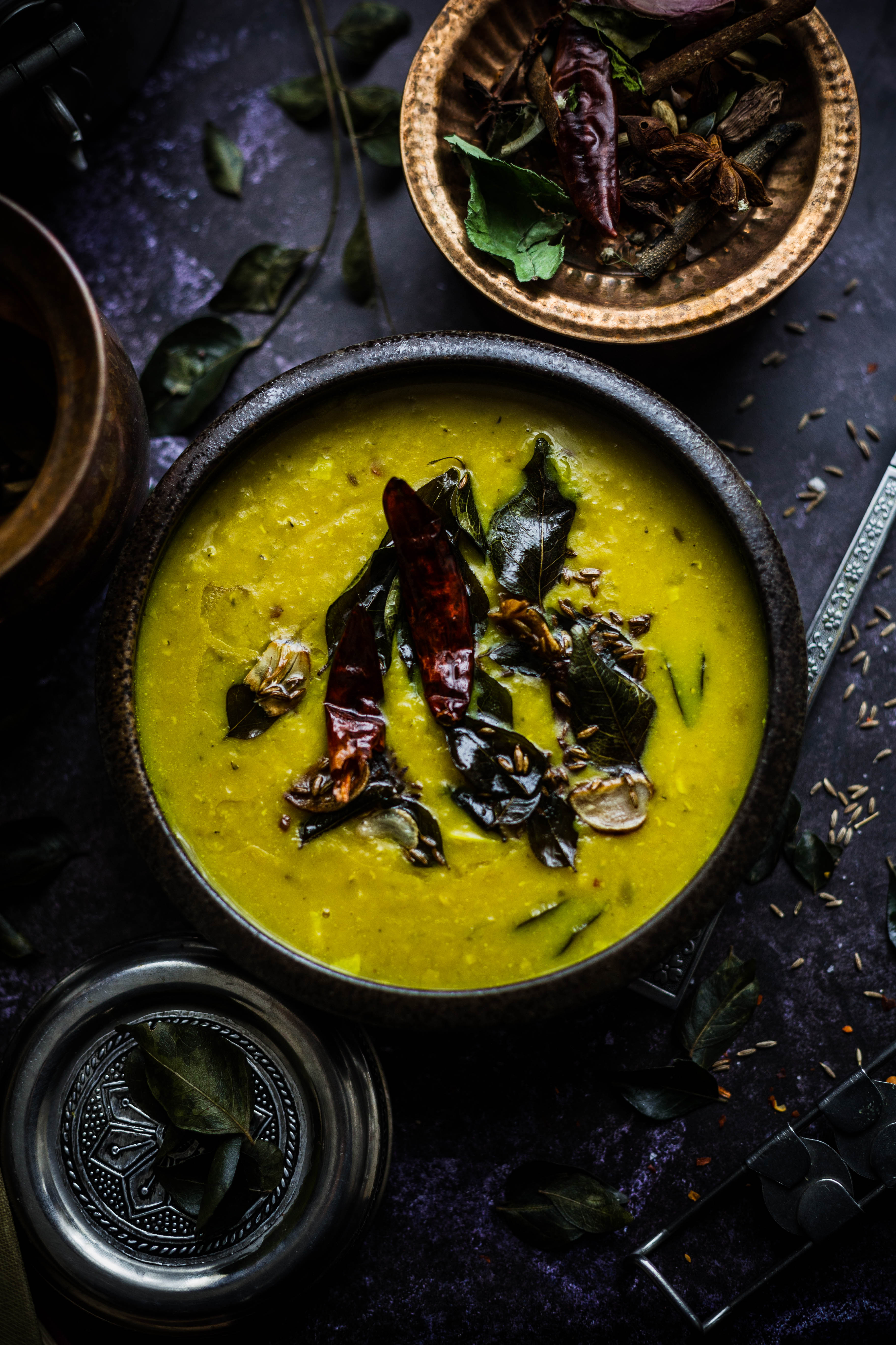 Masoor Dal Tadka in bowl with red chilli, curry leaves, garlic and cumin seeds on top