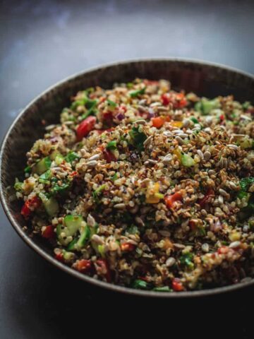 Vegetable and Herby Citrus Quinoa Salad in a bowl on black background