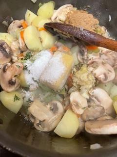 Garlic, Ginger and Spices added to pot with wooden spoon