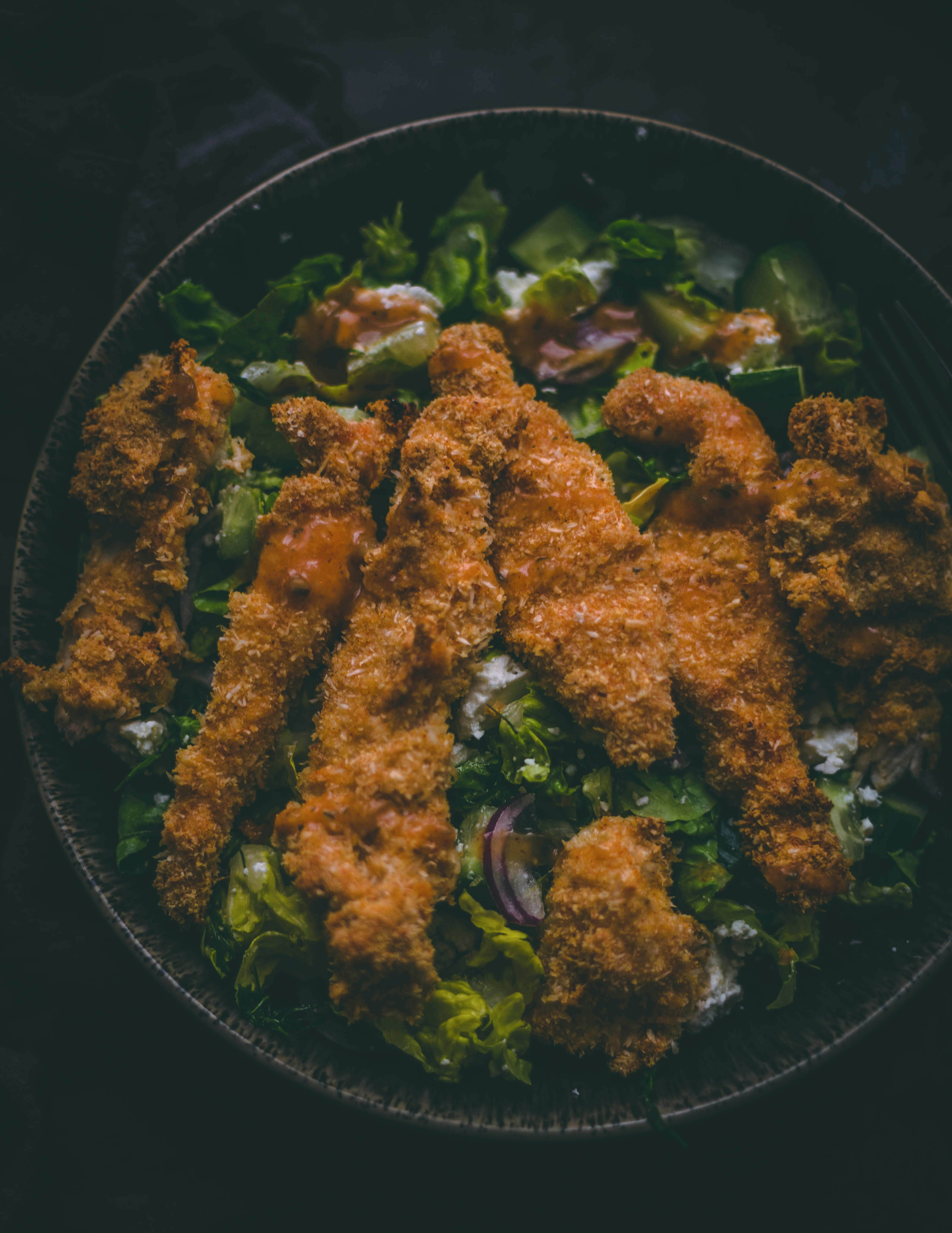 Crispy Almond Flour Chicken Strips on a bed of salad in a large bowl