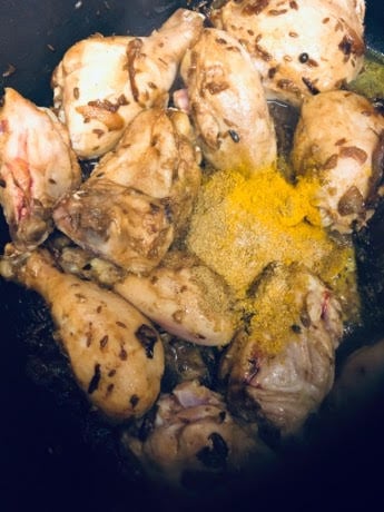Browned Chicken and spices in a pot with wooden spatula and Powdered Spices