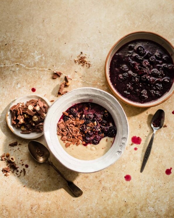 Talbina in a bowl with chocolate and stewed blueberries to side