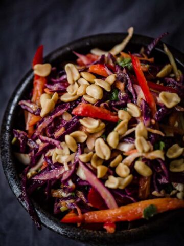 Red Cabbage, Red Pepper, Coriander and Peanuts in a black bowl on a grey towel