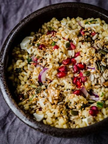 Barley Salad with Feta, Pomegranate and Mixed Seeds in a bowl on grey towel