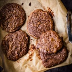 Chocolate Buckwheat cookies on greaseproof paper on a well used baking tray