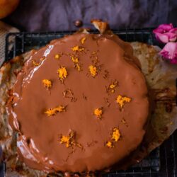 Chocolate orange cake with orange zest on greaseproof paper and grey towel