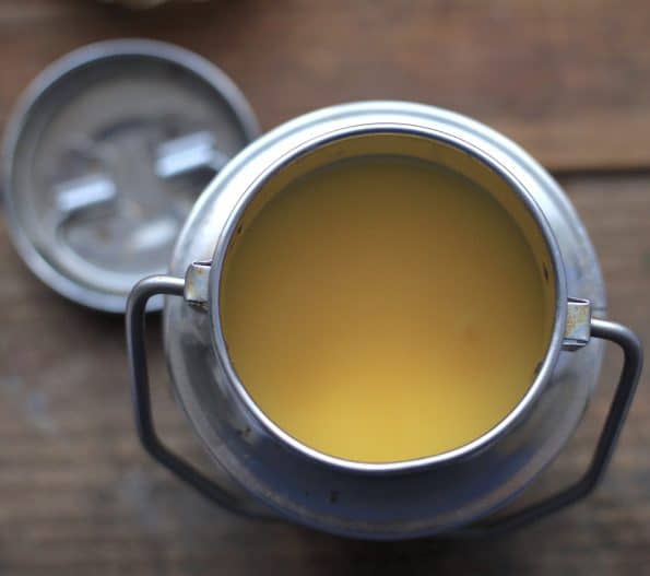 Solid Ghee in indian metal pot on wooden table