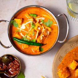 Paneer tikka masala in a dish with pickles and papadums