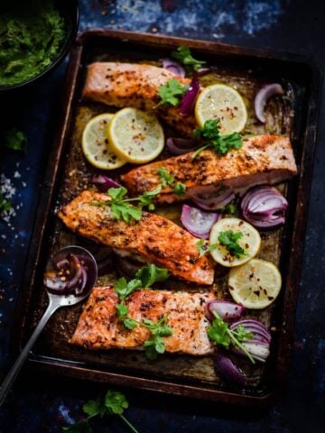 Salmon in a tray with lemons, red onions and coriander