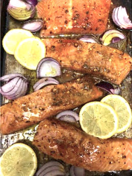 Salmon with marinade with red onions and lemons scattered around