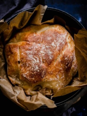 Baked bread in a cast iron pot on baking paper