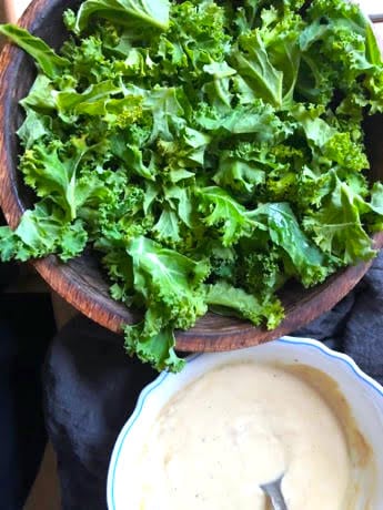 Kale in a bowl with tahini dressing to side in bowl