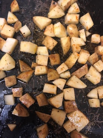 Cubes potatoes with oil on baking tray