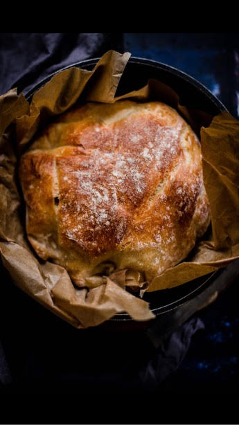 Baked bread in baking paper in cast iron pot