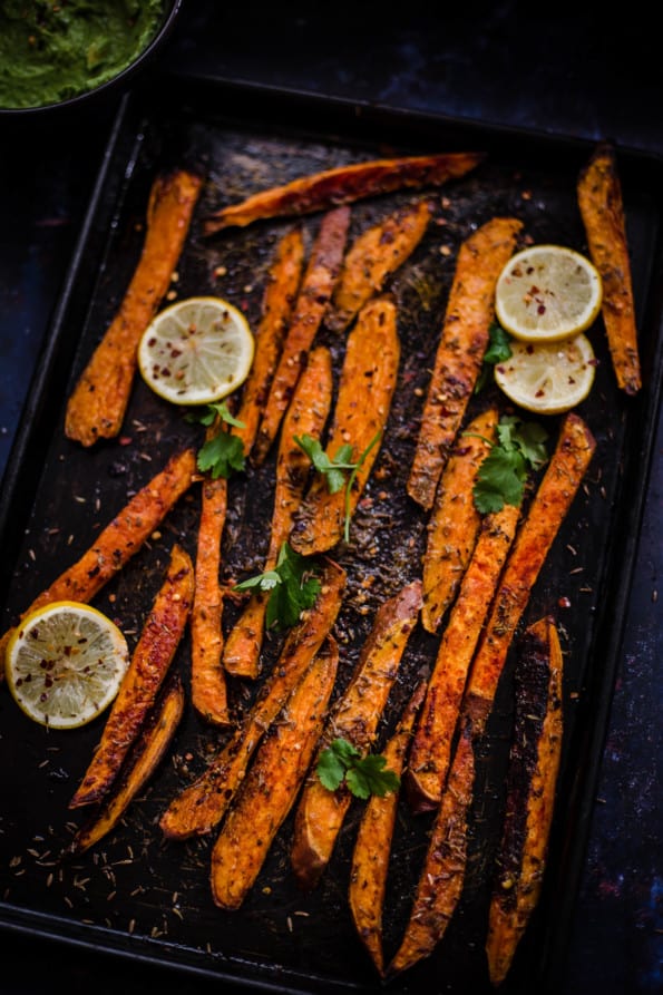 Oven baked sweet potato fries in a tray with lemons
