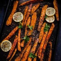Oven baked sweet potato fries in a tray with lemons