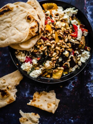 Roast veg with feta and pine nuts in bowl with flatbread to the side