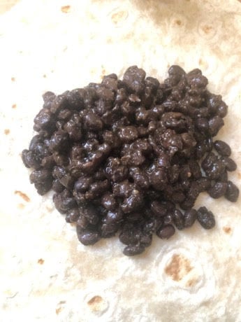 Cooked black beans on tortilla wrap