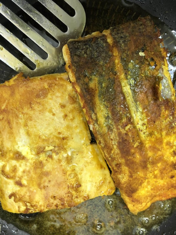 Fish being fried in frying pan