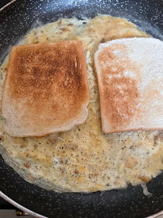Bread on top of omelette in pan