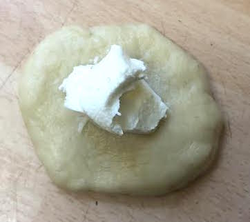 Piece of dough with cream cheese in centre
