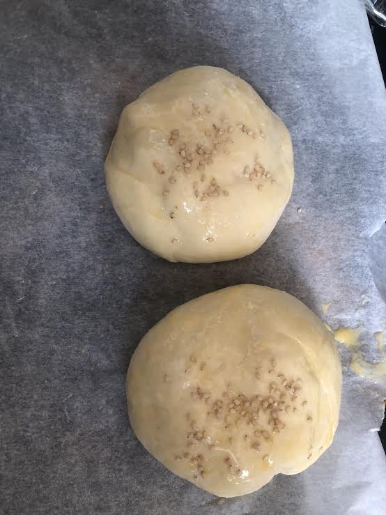 2 buns with egg wash and sesame seeds on lined tray