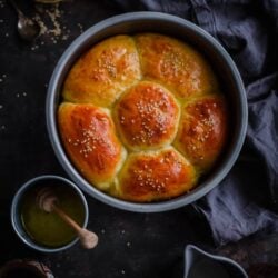Chicken milk buns in flower shape in round tin with butter to side