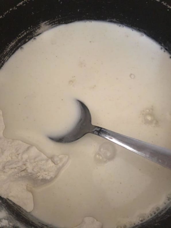 Milk and flour in pot with spoon